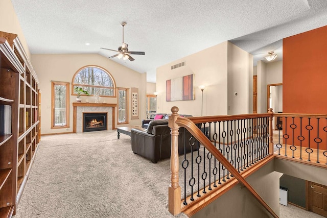 living area with lofted ceiling, carpet, visible vents, and a tile fireplace