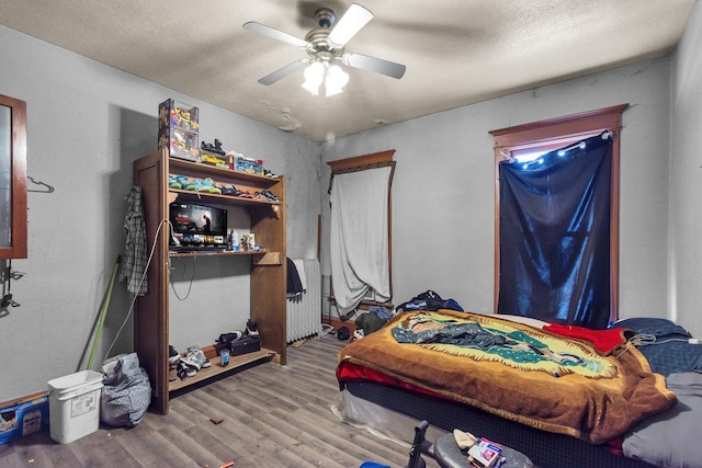 bedroom with a textured ceiling, wood finished floors, and ceiling fan