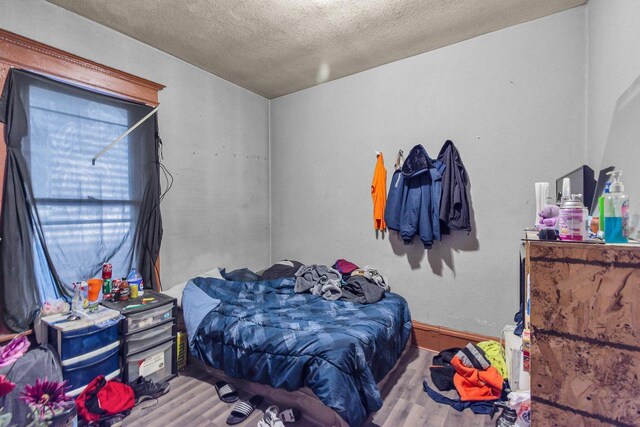 bedroom with a textured ceiling and wood finished floors