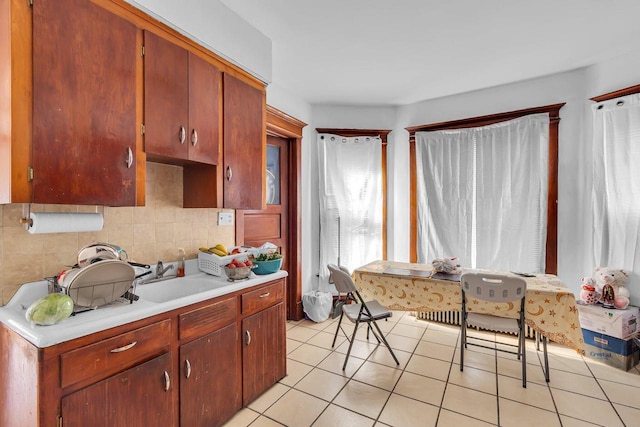 kitchen featuring light tile patterned flooring, decorative backsplash, light countertops, and a sink