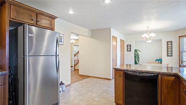 kitchen featuring a textured ceiling, black dishwasher, freestanding refrigerator, brown cabinetry, and a chandelier