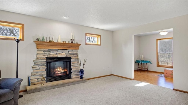 living area featuring a fireplace, a textured ceiling, baseboards, and carpet floors