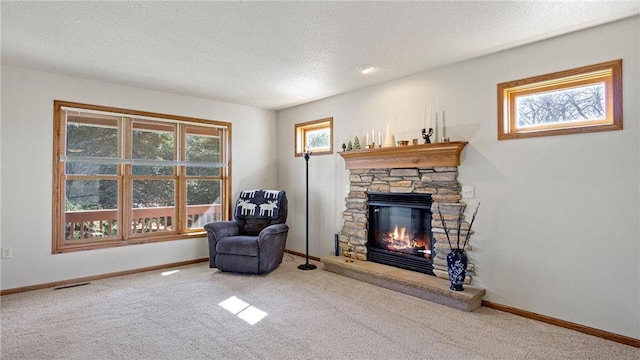 sitting room featuring baseboards, a textured ceiling, a stone fireplace, and carpet flooring