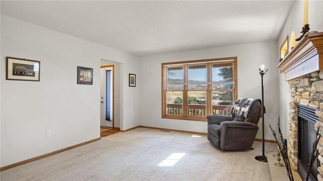 sitting room with visible vents, a textured ceiling, carpet floors, a fireplace, and baseboards