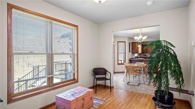 interior space with an inviting chandelier, baseboards, and light wood-type flooring