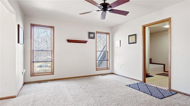 spare room with visible vents, ceiling fan, baseboards, and carpet floors