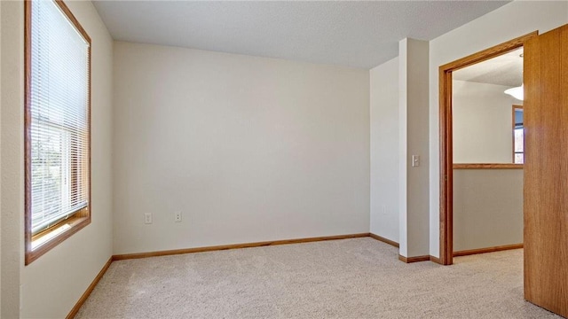 empty room with carpet, baseboards, and a textured ceiling