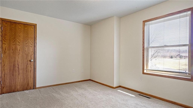 unfurnished room with baseboards, visible vents, and light carpet