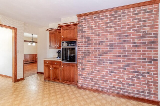 kitchen with oven, brown cabinets, light countertops, baseboards, and light floors