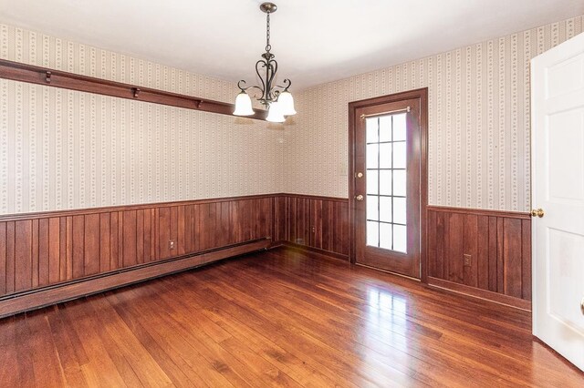 unfurnished room featuring wainscoting, wallpapered walls, a baseboard heating unit, and wood-type flooring