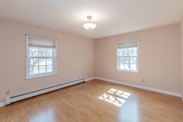 empty room with wallpapered walls, plenty of natural light, wood finished floors, and a baseboard radiator