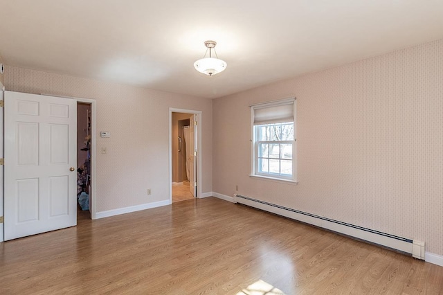 empty room with a baseboard heating unit, light wood-style flooring, and wallpapered walls