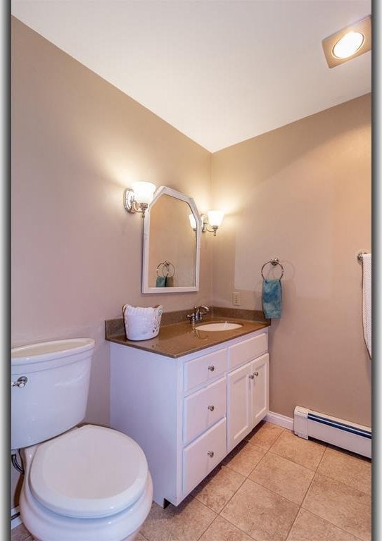 bathroom featuring tile patterned floors, toilet, baseboards, baseboard heating, and vanity