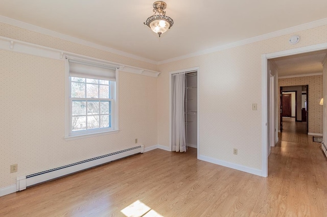 spare room featuring light wood-style floors, baseboard heating, ornamental molding, and wallpapered walls