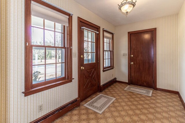 foyer entrance with wallpapered walls, baseboards, and a baseboard heating unit