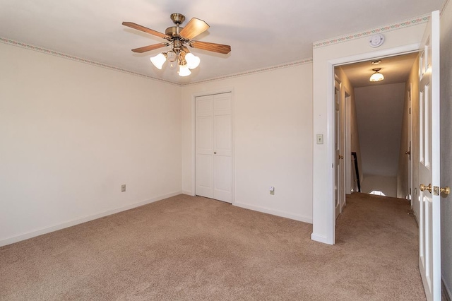 unfurnished bedroom with a closet, light carpet, baseboards, and a ceiling fan