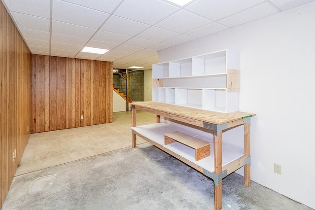 finished basement with stairway, wooden walls, and a drop ceiling