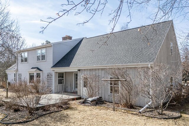 rear view of house with a patio, a chimney, and a shingled roof