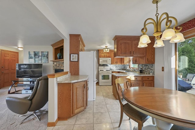 kitchen with tasteful backsplash, white appliances, an inviting chandelier, light tile patterned flooring, and light countertops