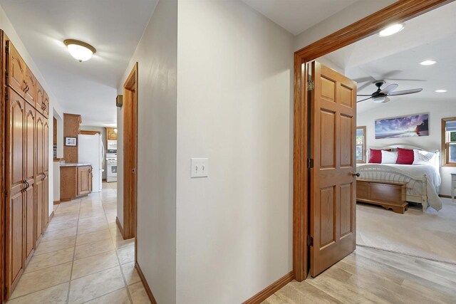 hallway with light tile patterned floors, baseboards, and vaulted ceiling