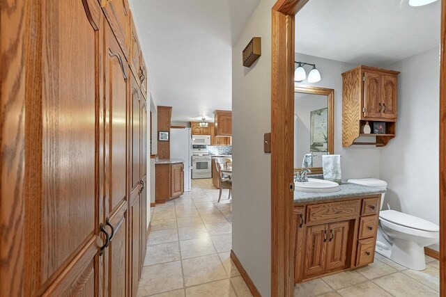 bathroom featuring baseboards, toilet, vanity, and tile patterned flooring