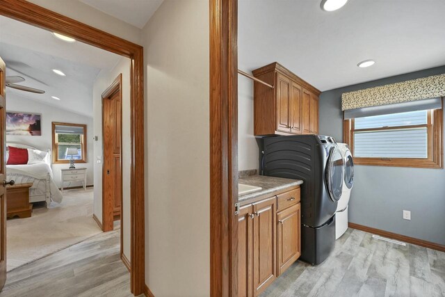 washroom featuring washing machine and dryer, cabinet space, light wood-style floors, and ceiling fan