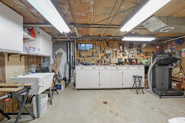 basement with visible vents, a workshop area, and a sink