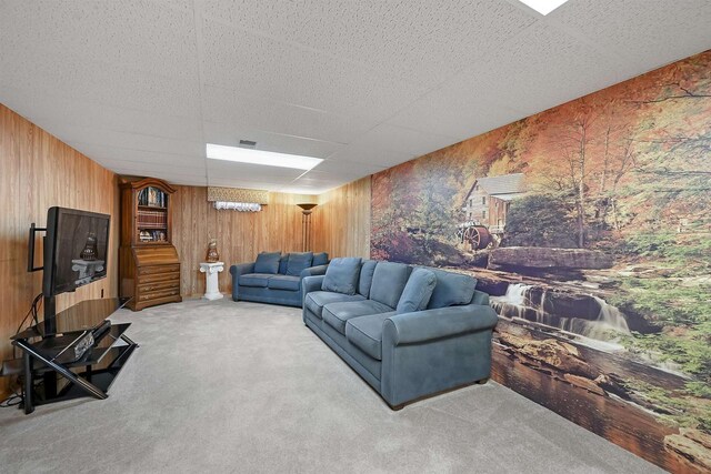 carpeted living room featuring visible vents, a paneled ceiling, and wooden walls