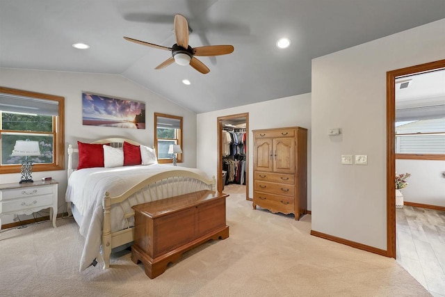 bedroom with baseboards, lofted ceiling, recessed lighting, a walk in closet, and light colored carpet