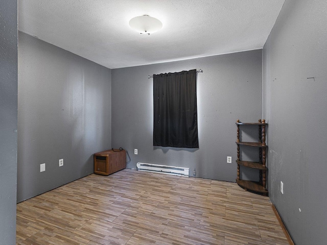 unfurnished room featuring baseboard heating, a textured ceiling, and wood finished floors