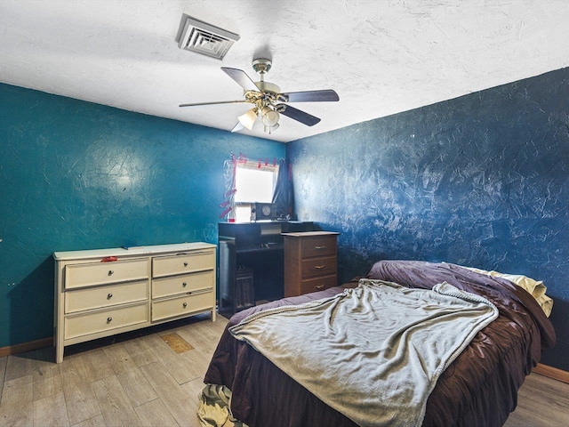 bedroom featuring ceiling fan, visible vents, a textured ceiling, and wood finished floors