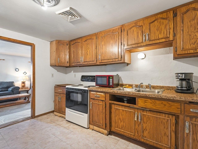 kitchen featuring visible vents, baseboards, white range with electric cooktop, brown cabinets, and a sink