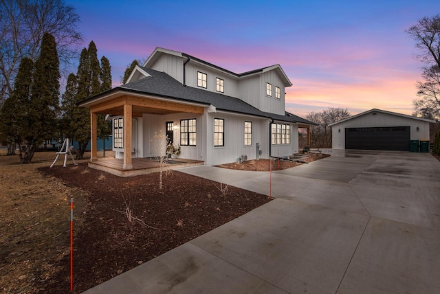 modern inspired farmhouse featuring board and batten siding, an outdoor structure, covered porch, and a detached garage