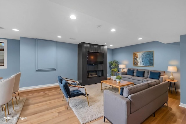 living area with light wood-style flooring, recessed lighting, and a large fireplace