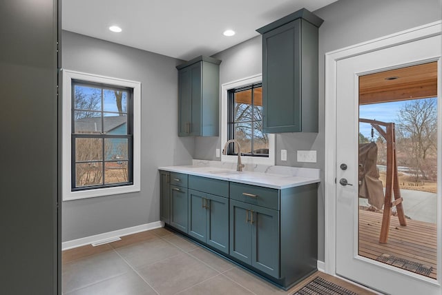 kitchen featuring baseboards, light stone countertops, recessed lighting, light tile patterned flooring, and a sink