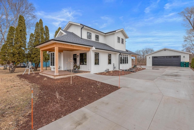 modern farmhouse with a porch, a shingled roof, an outdoor structure, a detached garage, and board and batten siding