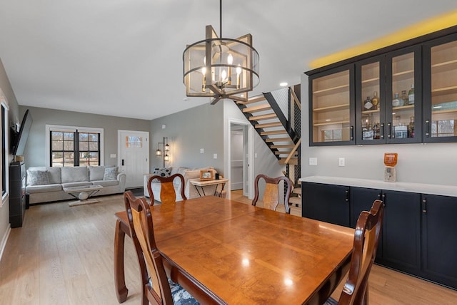 dining space with stairway, light wood-style floors, and a chandelier