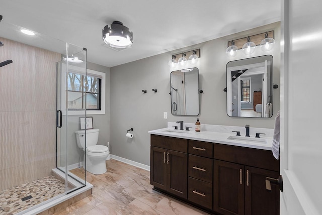 bathroom with a shower stall, toilet, baseboards, and a sink