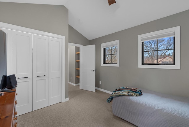 carpeted bedroom with a closet, baseboards, lofted ceiling, and a ceiling fan