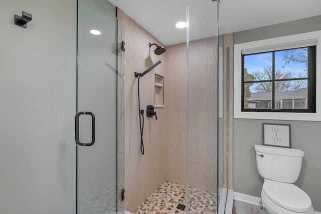 bathroom featuring toilet, baseboards, and a stall shower