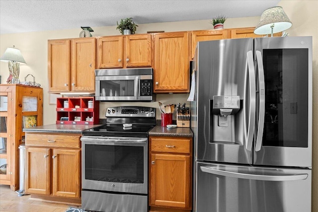 kitchen with stainless steel appliances, a textured ceiling, and dark countertops