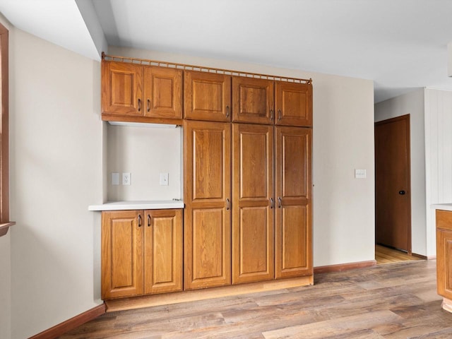 kitchen with brown cabinetry, baseboards, and light wood finished floors