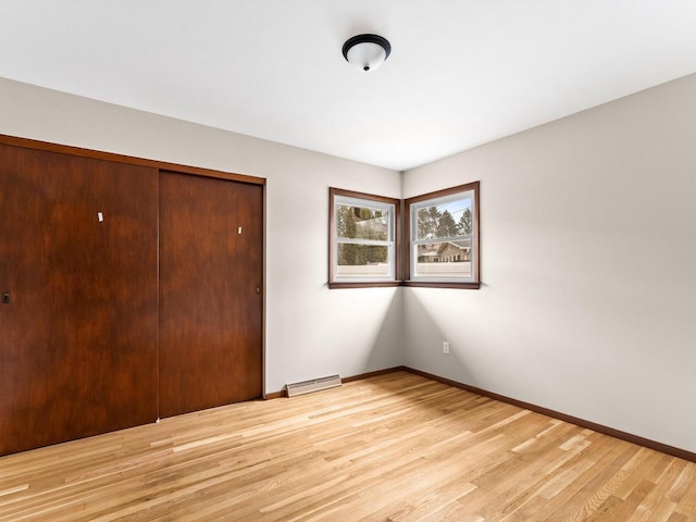 unfurnished bedroom with light wood-type flooring, baseboards, and a closet