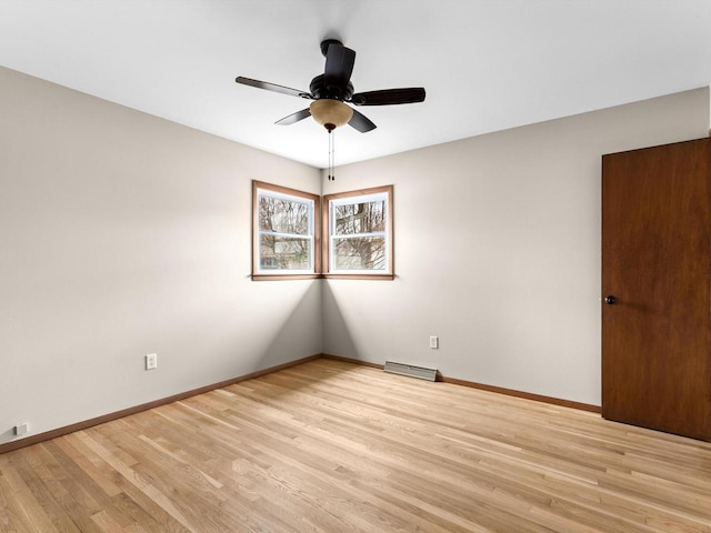 spare room with a ceiling fan, light wood-style flooring, visible vents, and baseboards