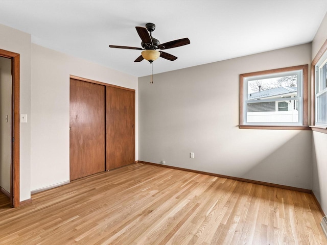 unfurnished bedroom featuring ceiling fan, light wood-style floors, a closet, and baseboards