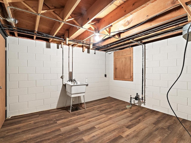 unfinished basement featuring a sink and dark wood-type flooring