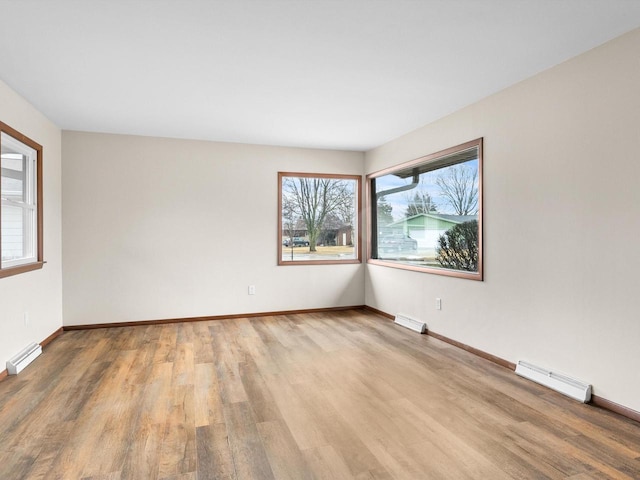 spare room featuring visible vents, baseboards, light wood finished floors, and a baseboard radiator