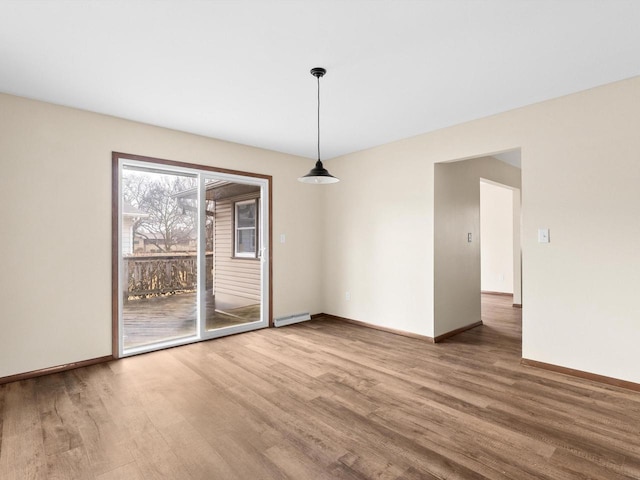 empty room featuring a baseboard radiator, baseboards, and wood finished floors