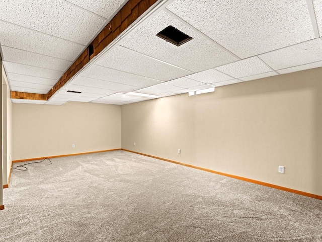 finished basement with a drop ceiling, baseboards, and carpet floors