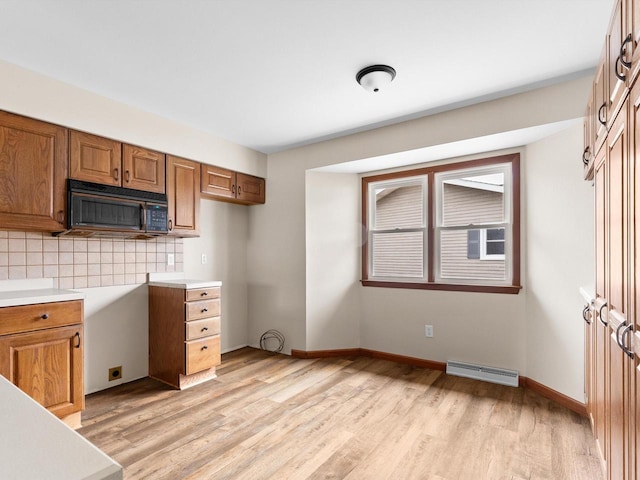 kitchen featuring light wood finished floors, brown cabinetry, visible vents, and black microwave